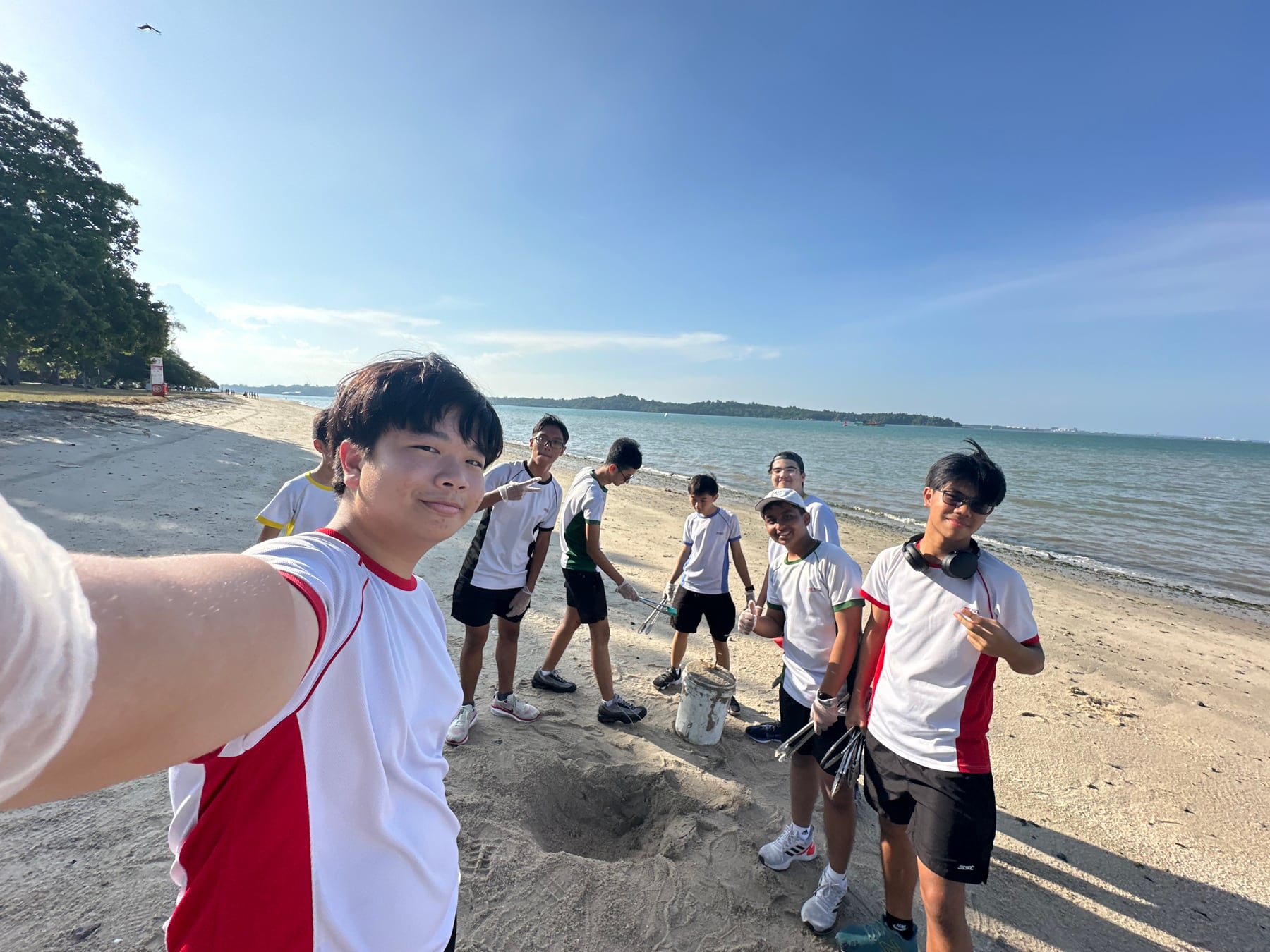 Students carrying litter-picking tools during the Changi Beach cleanup